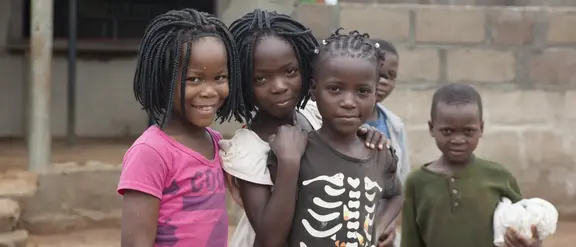 5 Schwarze Kinder, etwa im Grundschulalter, stehen beisammen und lächeln in die Kamera.