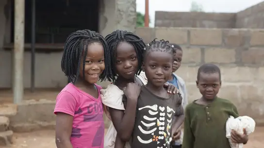 5 Schwarze Kinder, etwa im Grundschulalter, stehen beisammen und lächeln in die Kamera.